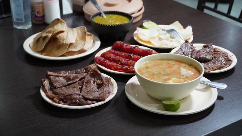 Mesa completa con carne asada, salchichas, frijoles charros y tortillas